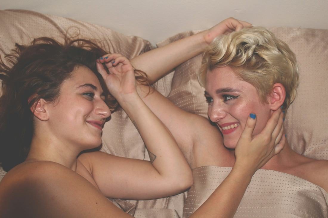 Two women laughing together in bed