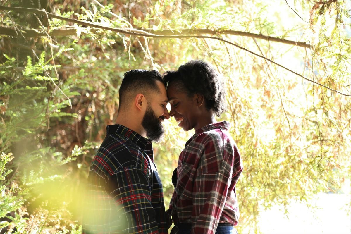 A couple standing forehead to forehead among trees